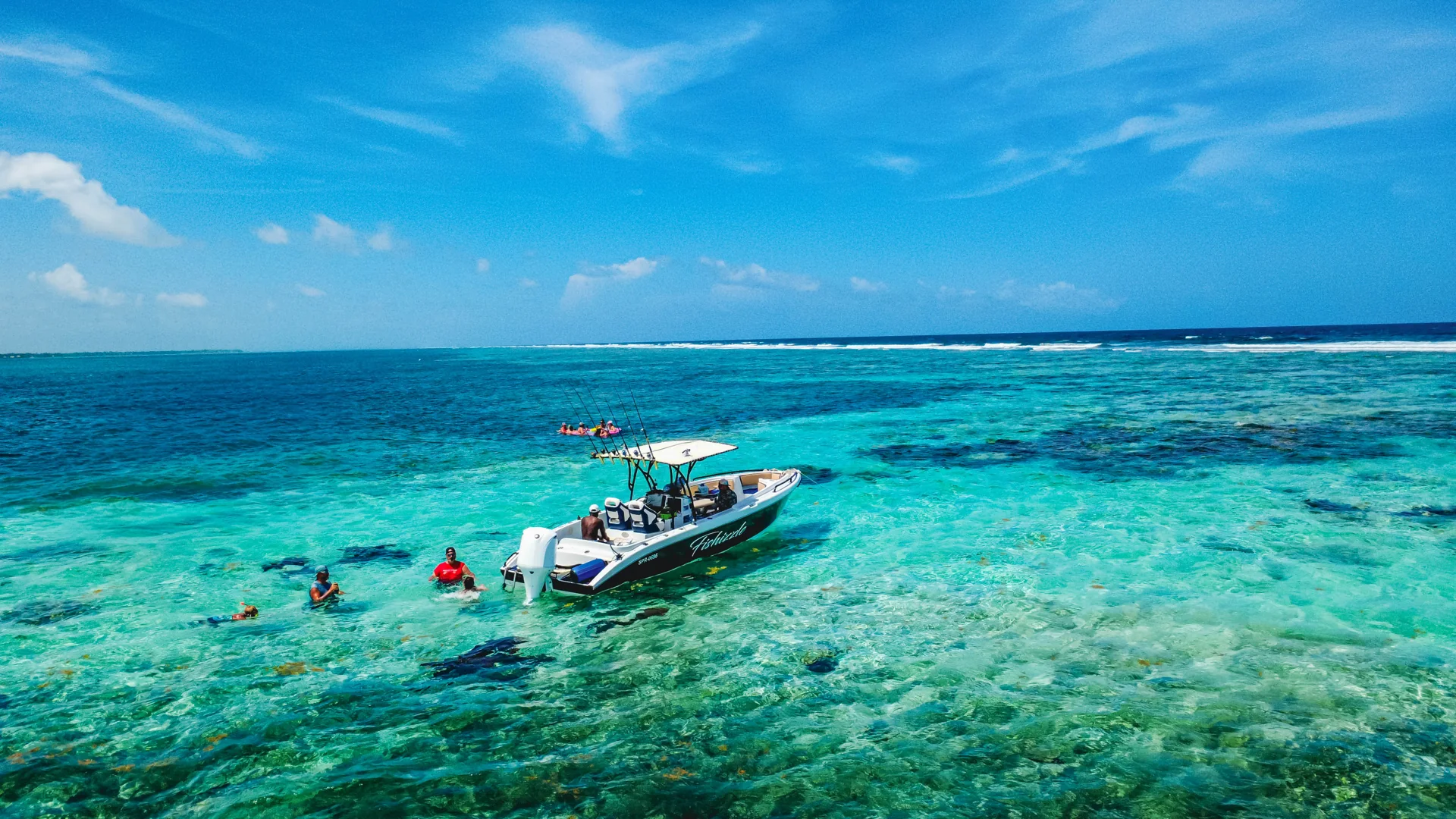 Swimmers beside Fishizzle in the clear Belize shallows